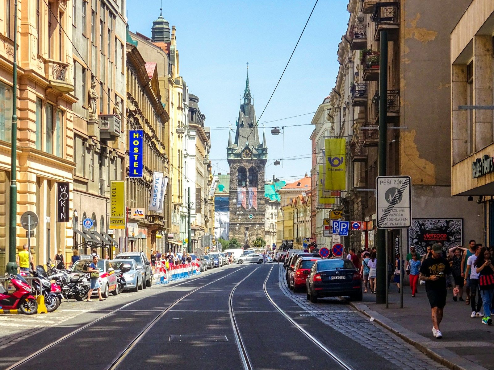 Pražská ulice s historickými domy a tramvajovými kolejemi.